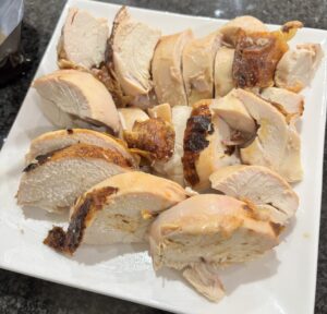 ロティサリーチキンの胸肉部分をスライスし、白い長方形の皿に並べた様子。